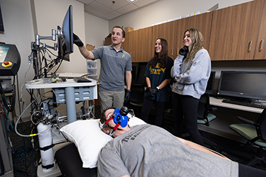 Kowalsky points to a screen while two people look on